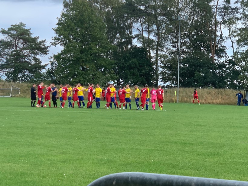 Begrüßung der Mannschaften vor dem Spiel. Warsow in gelb-blauer Spielkleidung, Cambs-Leezen in Rot.